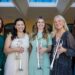 Five white women wear dresses and hold silver trumpets, The Calla Project.