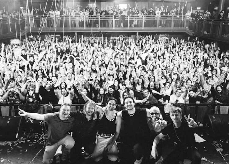 A black and white image of the band in front of a crowd at a show