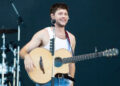 Niall Horan performing on stage and playing guitar at Superbloom Festival.
