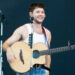 Niall Horan performing on stage and playing guitar at Superbloom Festival.