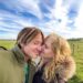Nicole Kidman kisses Keith Urban on the cheek under a blue sky with white clouds.