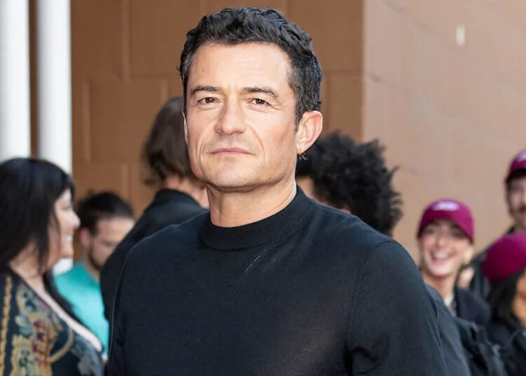 Orlando Bloom in a closeup on a red carpet.