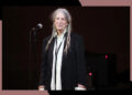 Patti Smith smiles while onstage in concert.