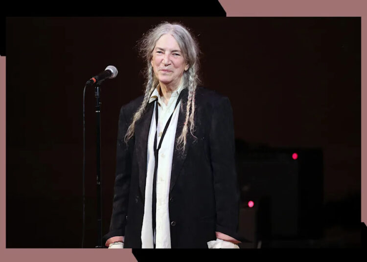 Patti Smith smiles while onstage in concert.