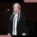 Patti Smith smiles while onstage in concert.