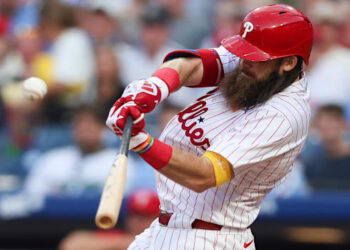 Philadelphia Phillies outfielder Brandon Marsh swings bat while wearing white uniform and red helmet