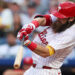 Philadelphia Phillies outfielder Brandon Marsh swings bat while wearing white uniform and red helmet