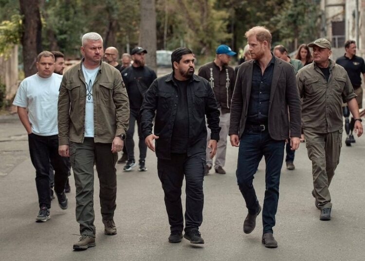 Three men walk next to each other talking with another group of people following behind.