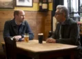 Prince William and Eugene Levy sitting at a bar table drinking beer