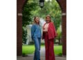 Princess Elisabeth wearing jeans and Queen Mathilde in a pink suit posing under an archway at Harvard