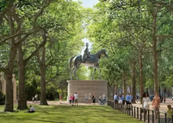 PA Media A mock-up of St James's Park with a large statue of Queen Elizabeth II on horseback high above ground. The statue sits on a plinth in between two rows of tall trees. People are milling about around it and on the pavement off to the right. It is daytime.