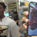 IShowSpeed in a store wearing a graphic t-shirt, with a phone showing a video call featuring Ray J.