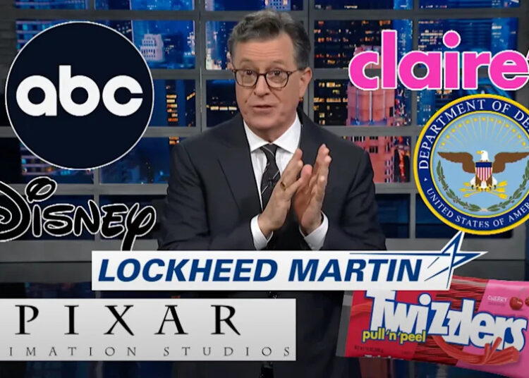 Stephen Colbert on set with logos of ABC, Claire's, Disney, Department of Defense, Lockheed Martin, Pixar, and Twizzlers.