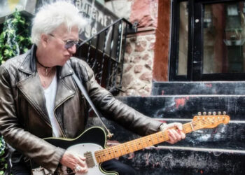 Ricky Byrd wears a weathered biker jacket and throws a pose as he plays a Telecaster on the stoop of a NYC apartment.
