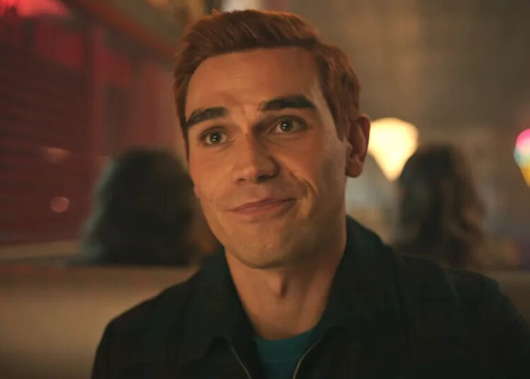 KJ Apa smiling as Archie while in Pop's in Season 7 of Riverdale .
