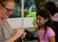 Sophia Hernandez, age 7, waits for the reveal of her face painting by Lisa Eklund at Music on Main. (Henry Huey/@HenryHueyPhoto)