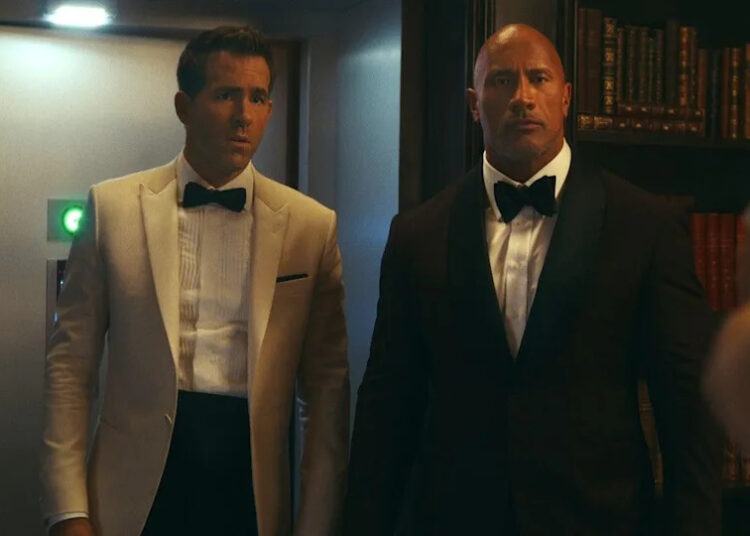 Dwayne Johnson and Ryan Reynolds in suits in Red Notice.