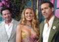 Hugh Jackman, Blake Lively and Ryan Reynolds pose together on the red carpet, smiling at the camera.