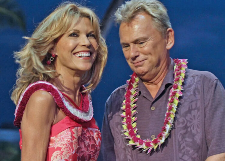 Vanna White and Pat Sajak share a laugh while wearing floral leis during a Wheel of Fortune taping in Hawaii.