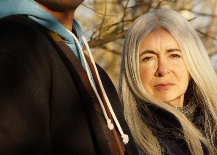 A man and a woman stand amid trees