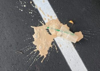 person standing on white line with cup on ground