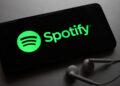 Spotify logo on a smartphone with headphones next to it