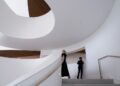 A woman and a boy walk up a white, spiral staircase.