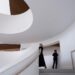 A woman and a boy walk up a white, spiral staircase.