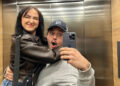 A man and woman hug while taking a selfie in a lift mirror
