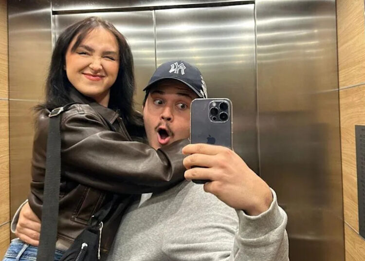 A man and woman hug while taking a selfie in a lift mirror
