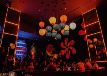 Lounge space at Gekkō, with red lighting, a blue backlit bar, and paper lanterns over center VIP seating
