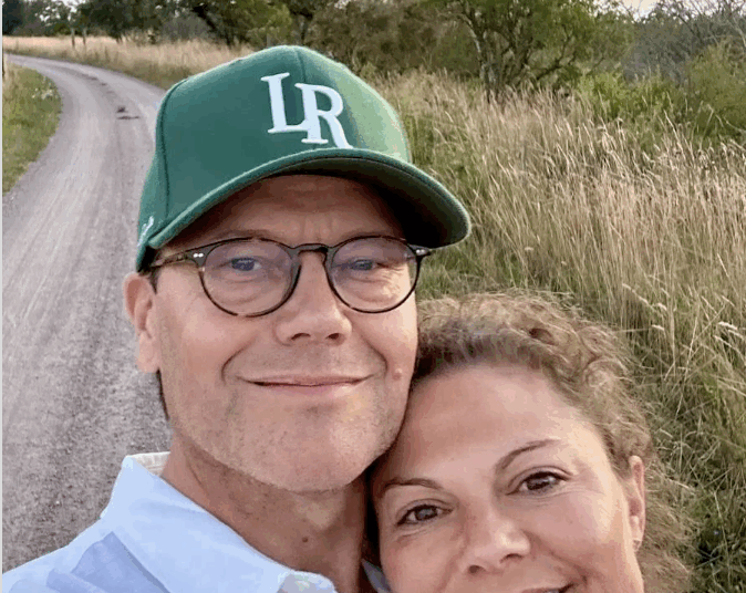 Crown Princess Victoria and Prince Daniel taking a selfie in front of a dirt road with a sunset behind them