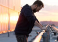 Noah Wyle dramatically leans on a railing at sunrise in The Pitt S1 E1 - "7:00 AM.".