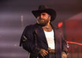Teddy Swims performs on stage in a cowboy hat.