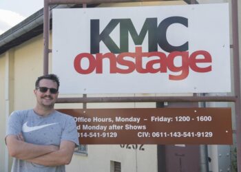 A man stands in front of a sign that says KMC Onstage.