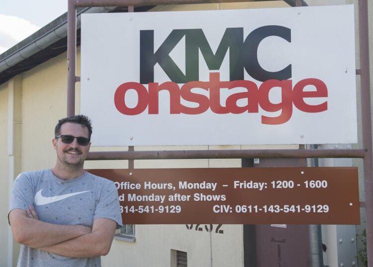 A man stands in front of a sign that says KMC Onstage.