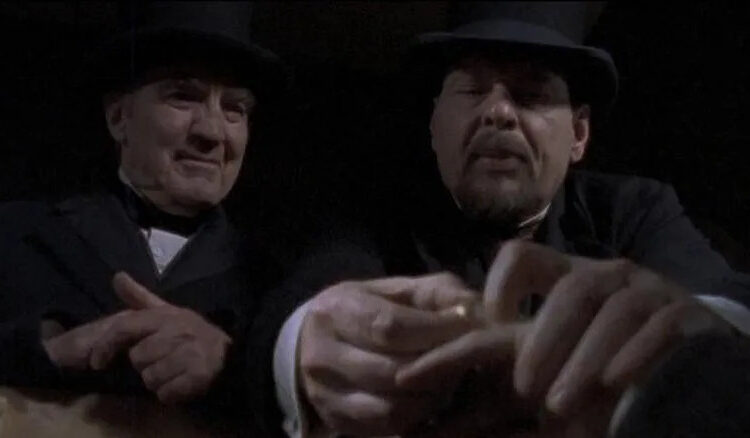 Two men in bowler hats inspecting a corpse in Dead Man's Gun