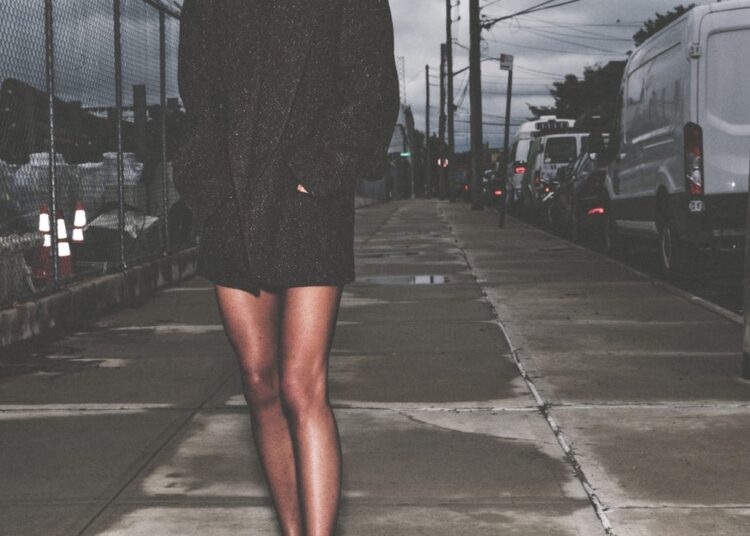 victoria beckham standing on a sidewalk in a dark blazer and high heels