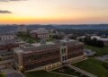 An aerial drone shot shows the Evansdale area of campus with the Agricultural Sciences building in the forefront and a golden skyline in the background.