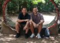 Scott and Sam sat down next to each other, smiling with their arms resting on their legs.