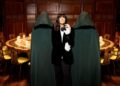 Claudia Winkleman in the middle of two cloaked individuals by The Traitors Round Table