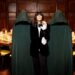 Claudia Winkleman in the middle of two cloaked individuals by The Traitors Round Table