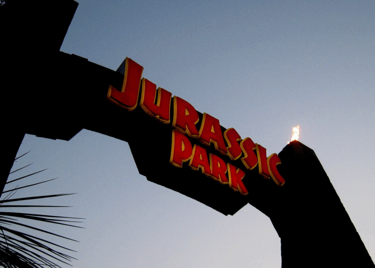 An arch with fiery torches reads "Jurassic Park" in red lettering
