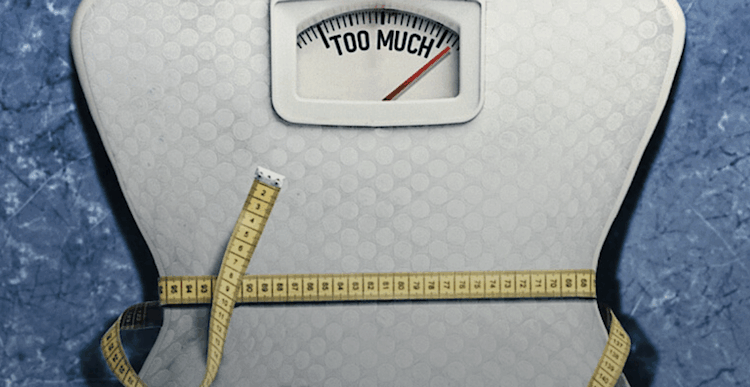 A set of scales saying 'TOO MUCH' pulled in at the centre with a measuring tape