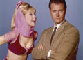 Barbara Eden making a funny face to Larry Hagman as she looks annoyed.