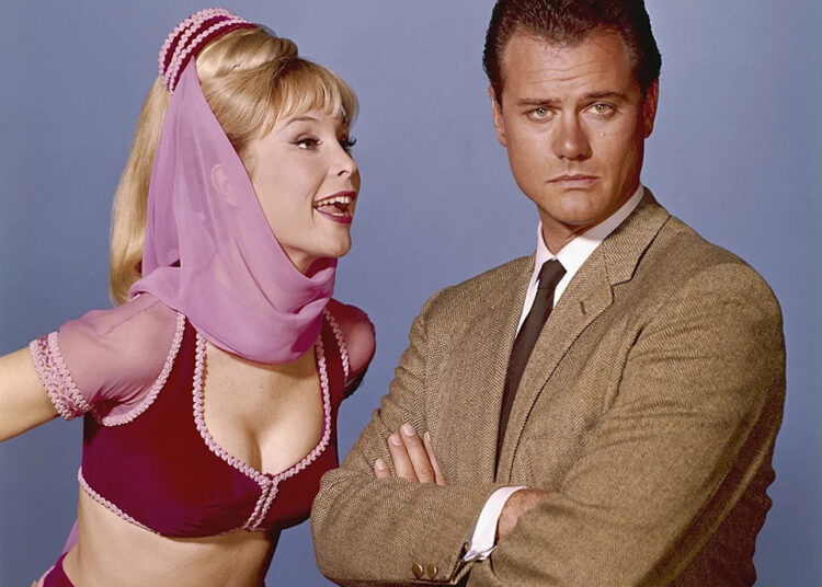 Barbara Eden making a funny face to Larry Hagman as she looks annoyed.