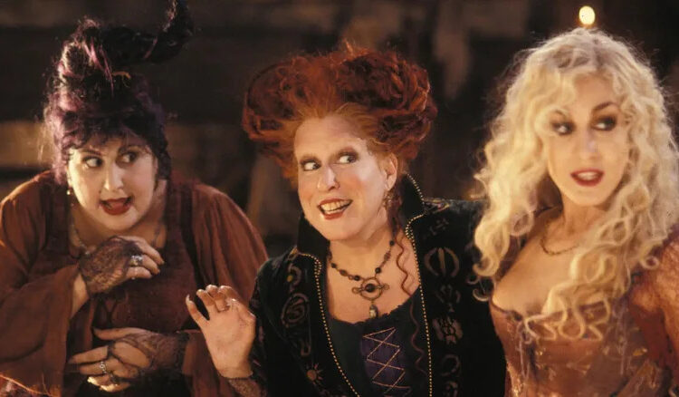 Kathy Najimy, Bette Midler, and Sarah Jessica Parker as the Sanderson sisters stand side-by-side in Hocus Pocus