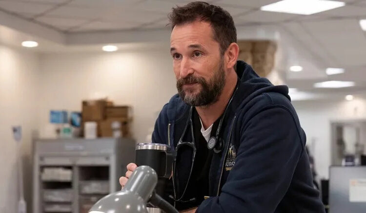 Dr. Robby holds a metal coffee mug with his eyebrows raised on The Pitt