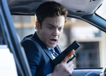 Nathan looking at his hand holding a gun in "Novocaine" (2025)