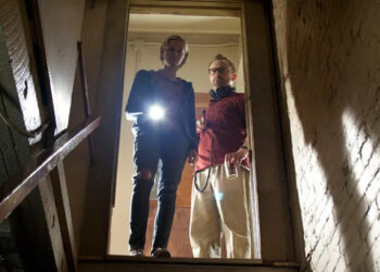 Claire and Luke peer down the stairs into the basement in The Innkeepers